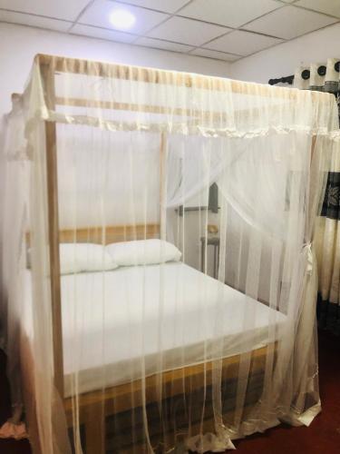 a canopy bed with white curtains in a room at Chill corner in Ahangama