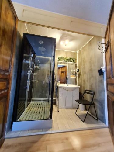 a large glass shower in a bathroom with a chair at Au fil du temps 54 in Lironville