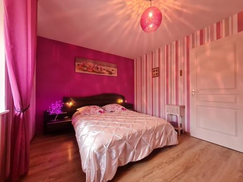 Una habitación rosa con una cama y una pared rosa. en Les Glycines, en Choloy