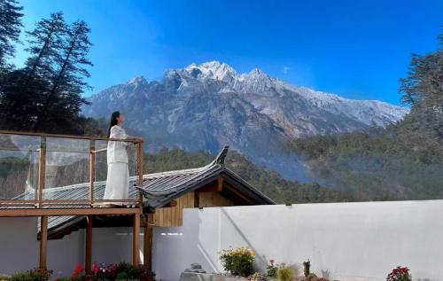 a woman standing on a balcony looking at a mountain at Lijiang Hengchang Baoyin Mohuakai Inn in Lijiang