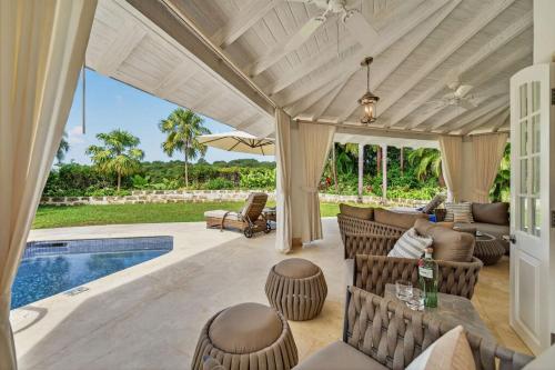 an outdoor patio with chairs and a swimming pool at Royal Westmoreland - Villa Grove home in Saint James