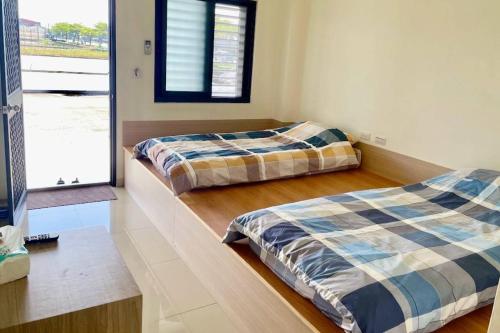 two beds in a room with a window at 宜蘭好窄平價民宿 in Zhuangwei