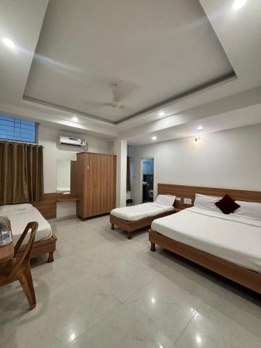 a large room with two beds and a table at Seema Palace Inn 1 km from Railwaystaion in Mysore