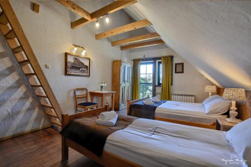 a attic room with two beds and a staircase at Zagroda Magija Bieszczady in Orelec