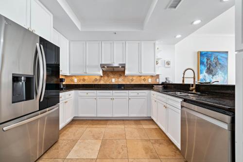 una cucina con mobili bianchi e un frigorifero in acciaio inossidabile di Indigo Unit 903W a Perdido Key