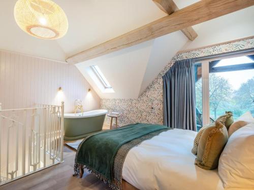 een slaapkamer met een bed, een bad en een raam bij 1 Bed in Alton oc-95760 in West Worldham