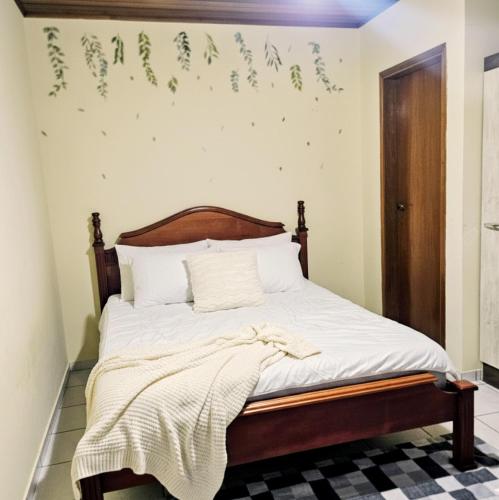 a bedroom with a bed with white sheets and green leaves on the wall at Villa Enseada - Charme e conforto a 650m da Praia da Enseada in Guarujá