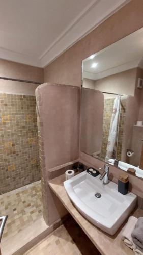 a bathroom with a white sink and a shower at Appartement Ksour in Sraghna