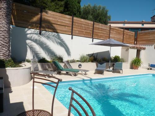 une piscine avec des chaises et un parasol dans l'établissement La Villa du Petit Port, à Martigues