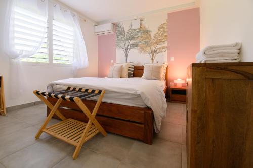 een slaapkamer met een groot bed en een stoel bij Cosy T2 clim - Piscine - À 5 min des plages de Saint-François in Saint-François