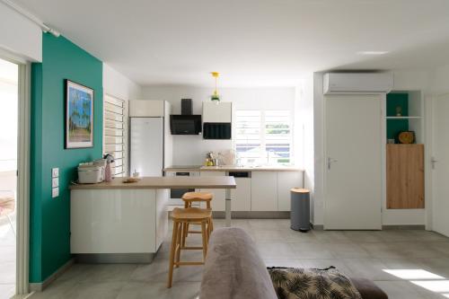 een keuken met witte kasten en een groene muur bij Cosy T2 clim - Piscine - À 5 min des plages de Saint-François in Saint-François