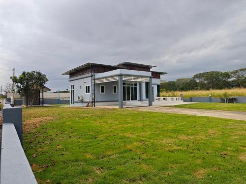 Haru Home Khaoyai في Nong Nam Daeng: مبنى أبيض صغير مع ميدان عشبي