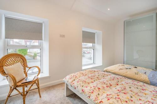 a bedroom with a bed and a chair and two windows at 4 Bed in Killay oc-c28372 in Killay