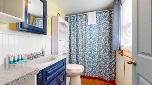 a bathroom with a toilet and a blue shower curtain at Sand Life #2 by Bayley Vacation Rentals in Old Orchard Beach