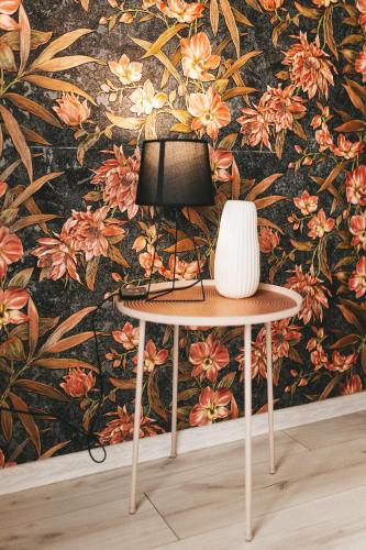 a table with a vase on it in front of a floral wall at Cosmic апартаменти з ванною in Ternopil