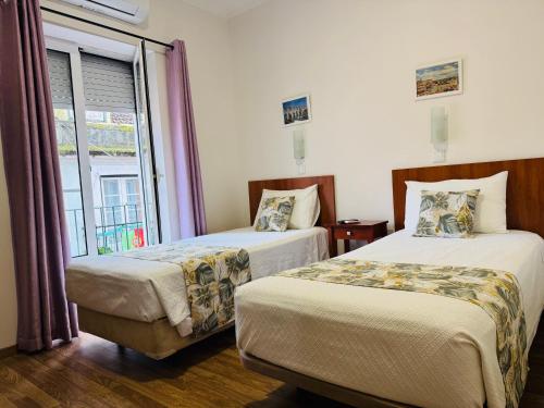 a hotel room with two beds and a window at Residencial Camoes in Lisbon
