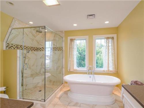 ein großes Badezimmer mit Badewanne und Dusche in der Unterkunft Happy Holidays with Sea Breeze in Surfside