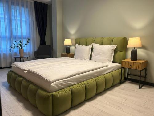 ein Schlafzimmer mit einem großen Bett mit grünem Kopfteil in der Unterkunft Apart Hotel Danaya in Stara Sagora