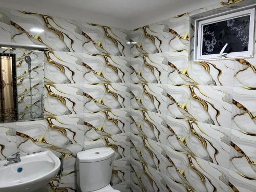 a bathroom with a gold and white wallpaper at White House Family Stay in Maspota