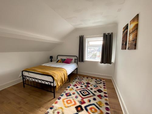 a small bedroom with a bed and a rug at Spacious 4-bedroom - 2 full Bathrooms home - Private off-road Parking - Centrally located in Bridgend