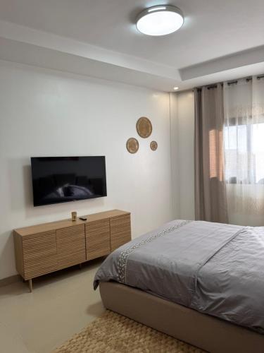 Un dormitorio con una cama y un televisor de pantalla plana. en Sublime T2 Lumineux et Calme, en Dakar