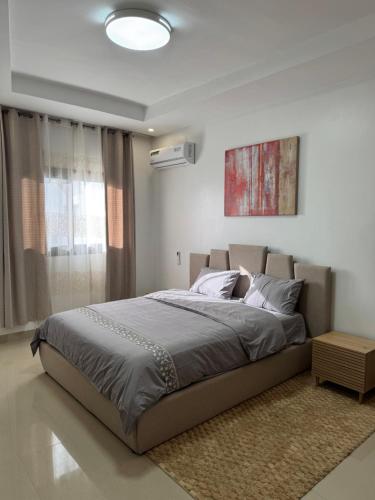 Un dormitorio con una cama grande y un cuadro en la pared. en Sublime T2 Lumineux et Calme, en Dakar