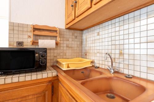 une cuisine avec un évier et un micro-ondes dans l'établissement Edelweiss - Grust, Panoramique Sud, à Grust