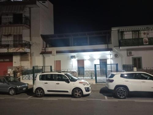 dwa białe samochody zaparkowane na parkingu przed budynkiem w obiekcie Mary&Bi w mieście Scalea