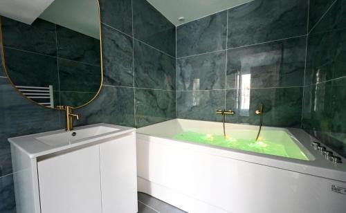 ein Badezimmer mit Badewanne und großem Spiegel in der Unterkunft Le Sens - Duplex 4 pers - Love Room - Jacuzzi in Sens