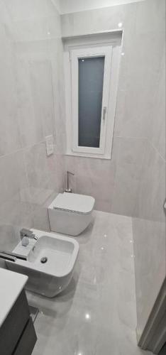 a white bathroom with a toilet and a sink at B&B Grifondoro in Crotone