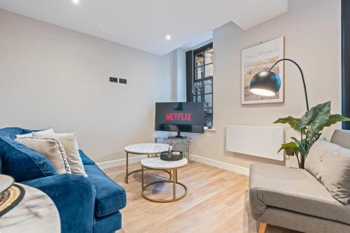 Una sala de estar con un sofá azul y un televisor en Studio Seven - Leeds City Centre, en Central Station