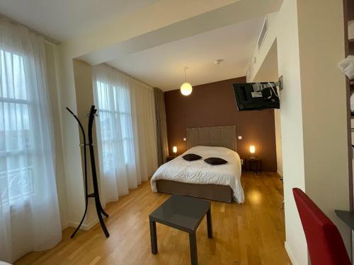 Hôtel Le Riche'Lieu في لوكون: غرفة نوم مع سرير وتلفزيون بشاشة مسطحة