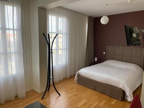 Hôtel Le Riche'Lieu في لوكون: غرفة نوم بسرير وملاءات بيضاء ونوافذ