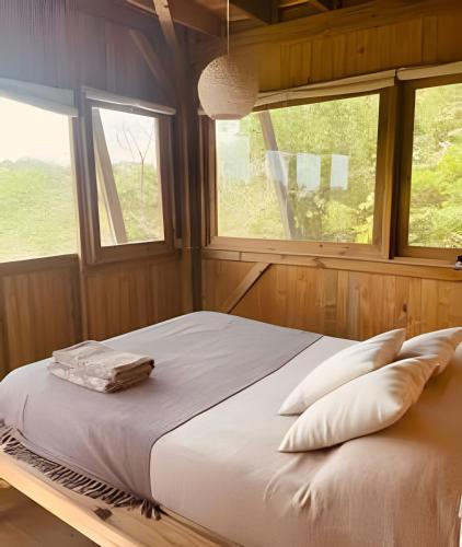 a bed in a room with two windows at Casa Fluila in Praia do Rosa