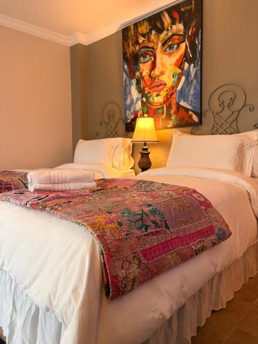Caye Caulker Boutique Guesthouse 4 في كاي كولكر: سريرين في غرفة مع لوحة على الحائط