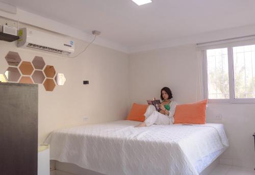 eine Frau, die auf einem Bett in einem Zimmer sitzt in der Unterkunft Villa Malibu in Taganga