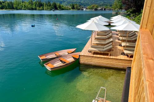 a dock with umbrellas and boats on a lake at Strandhotel Margaretha in St. Wolfgang