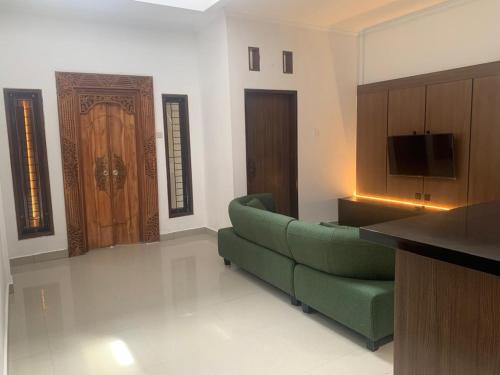 ein Wohnzimmer mit einer grünen Couch und einer Tür in der Unterkunft Cahaya Residence The Guest House in Kuta