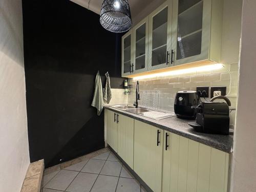a kitchen with white cabinets and a sink at Cozy Garden Cottage for Two in Cape Town