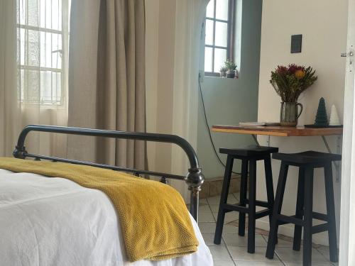 a bedroom with a bed and a table and chairs at Cozy Garden Cottage for Two in Cape Town