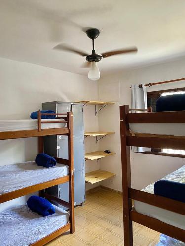 a room with bunk beds and a ceiling fan at Cosmopolitans Hostel in Ubatuba