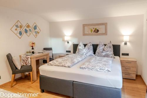 a bedroom with a large bed with a desk and a chair at Haus Panorama in Brixen im Thale