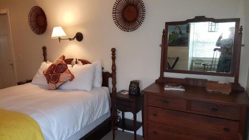 a bedroom with a bed and a dresser with a mirror at The Caribbean Court Boutique Hotel in Vero Beach