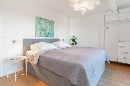 ein Schlafzimmer mit einem Bett und einem Gemälde an der Wand in der Unterkunft Gollings am See Gingko-Suite in Bosau