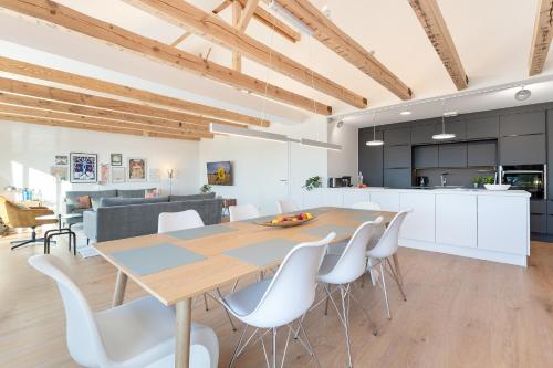 a kitchen and dining room with a wooden table and white chairs at Gollings am See Loft-Suite in Bosau