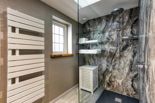 a bathroom with a shower and a stone wall at Courtyard Cottage in Castle Douglas