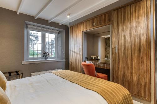 a bedroom with a bed and a desk and a window at Courtyard Cottage in Castle Douglas