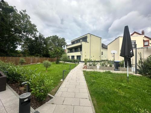 ein Garten mit einem Gebäude und einem Sonnenschirm in der Unterkunft Hotel Athen Kelsterbach Frankfurt Airport in Kelsterbach