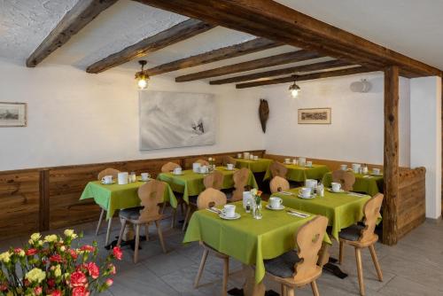 a restaurant with green tables and chairs and flowers at Annex Antika in Zermatt