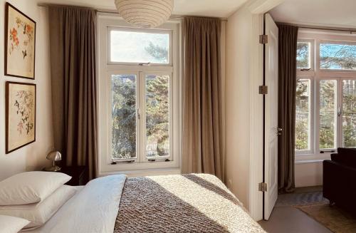 a bedroom with a bed and two windows at Top Floor Apartment Vondelpark in Amsterdam